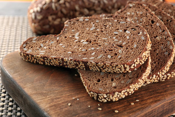 Sliced bread with seeds and sesame on wooden cutting board closeup