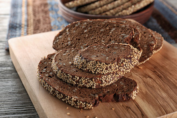 Sliced rye bread with seeds and sesame on wooden cutting board closeup