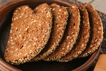 Sliced rye bread with seeds and sesame in clay bowl closeup