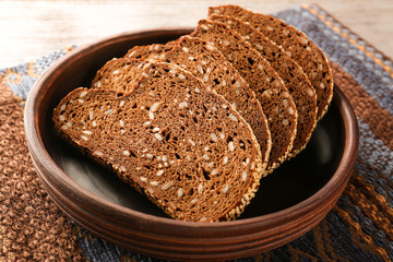 Sliced rye bread with seeds and sesame in clay bowl closeup