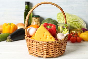 Variety of food products in basket on wooden background