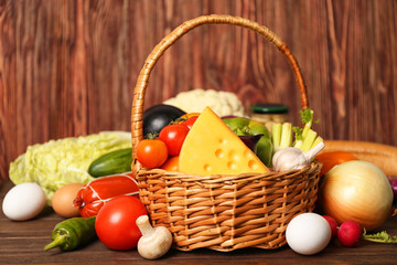 Variety of food products in basket on wooden background