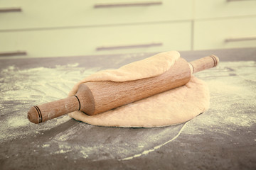 Rolling pin with dough on kitchen table