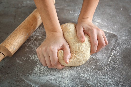 Woman hands kneading dough on kitchen table