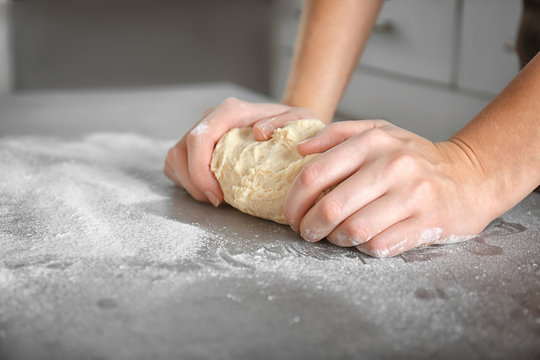 Woman hands kneading dough on kitchen table