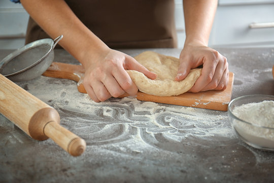 Woman hands kneading dough on kitchen table