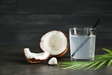 Glass of coconut water and fresh nut on dark background