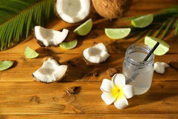 Fototapeta na wymiar Glass of coconut water and beautiful plumeria flower on wooden background