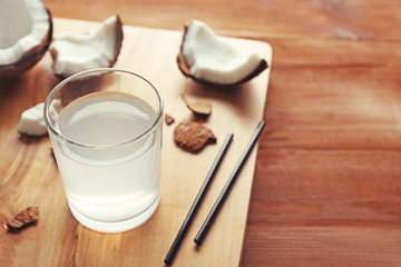 Glass of coconut water and fresh nuts on wooden board