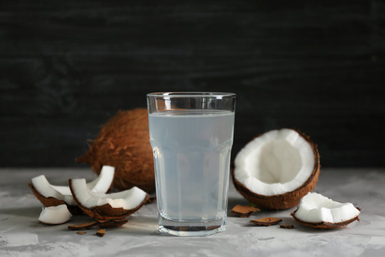 Glass of coconut water and fresh nuts on dark background