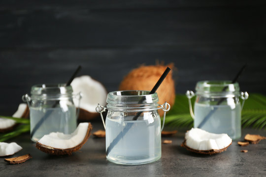 Three mason jars with coconut water and fresh nuts on dark background