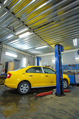 Yellow taxi under repair in a car repair station