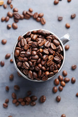 Roasted coffee beans in mug on grey table