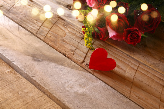 Red heart and roses on wooden table