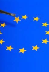 European Union flag with one of the stars as member removed and held in tweezers. Concept of Brexit as Britain vote to leave.