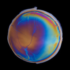 Vivid multicolored circle created by iridescent oil spill  film isolated on black background