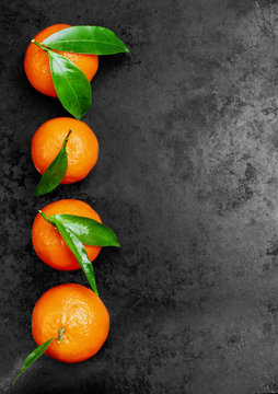 Fresh tangerines with leaves on black metal background. Top view, copy space