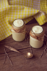 yogurt in jars on the wooden table with napkin, spoon and dried