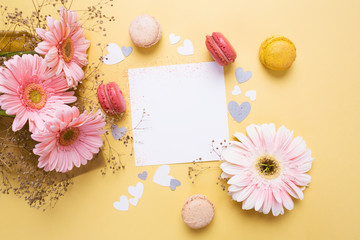 Naklejka na ściany i meble pink flowers and colored macarons on yellow background