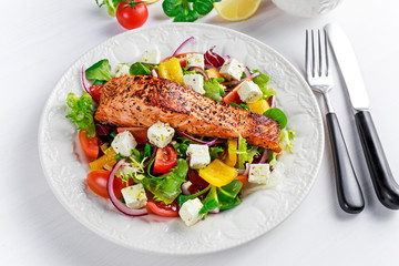 Fried Salmon steak with fresh vegetables salad, feta cheese. concept healthy food.