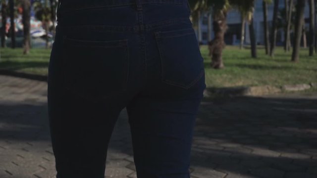 Concept: business, shopping, savings, money. Attractive girl pulls and puts back in the jeans pocket stack of dollar bills. Slow motion 60fps. HD