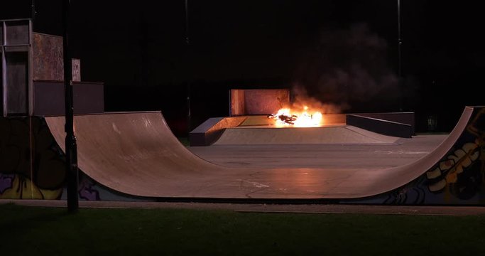 4K Camera reveals a skate park at night where a fire blazes