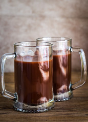 Two mugs of hot chocolate on the wooden background