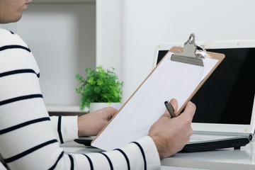 hand with the pen and the folder in the office with the laptop, closeup
