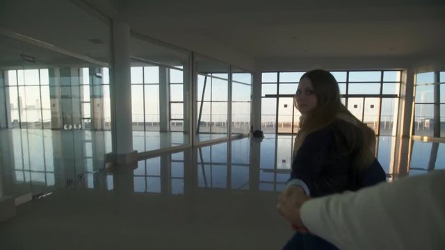 Concept: happiness, relationships, millennial. Cute girl taking the viewer by hand and walking in a modern building at sunset (follow me). POV shot. HD 1080p. Slow motion 60fps.