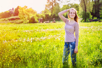Naklejka na ściany i meble young woman walking in a meadow with yellow wildflowers