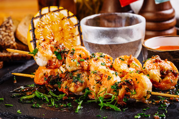 roasted shrimps on skewers with sauce and lemon.