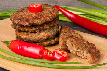 liver pancakes or cutlets with chili pepper and green onions on a wooden background