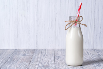 Bottle of milk with red straw, wooden background