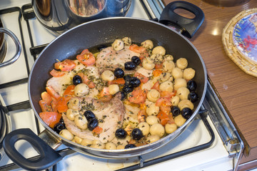 pork steak in the pan with cherry tomatoes black olives and mushrooms