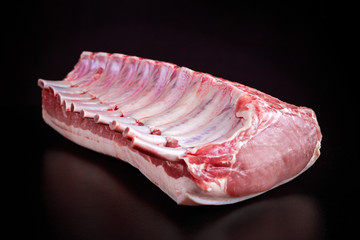 Fresh Raw French whole rack of pork loin with ribs on black board.