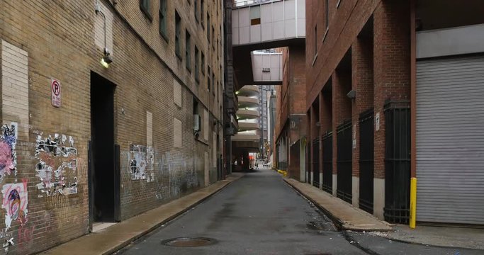 A daytime overcast establishing shot of an empty alley in a big city.  	