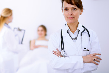 Fototapeta premium Female doctor smiling on the background with patient and his doctor