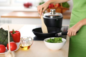 Fresh vegetables, salad and vegetable oil at the background of  woman is cooking by the stove in the kitchen
