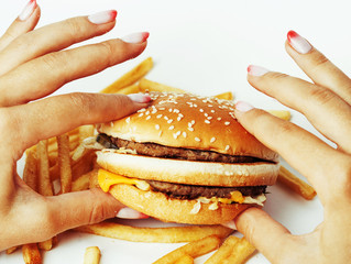 woman hands with manicure holding hamburger and french fries iso