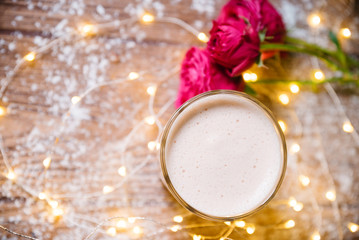 Cup of coffee with macaroons and roses on wooden table