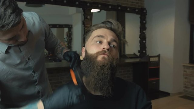Handsome man with a long beard and undercut in barbershop