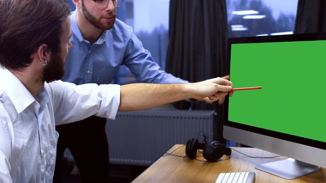 Two developers working on a project at trendy start up office, discussing project on a computer screen. Chroma key. 4K UHD 60 FPS slow motion