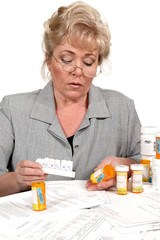 Older woman checks the prescription instructions before filling pill dispenser