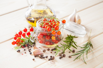 tomatoes in a jar, rosemary and garlic on a wooden background, selective focus