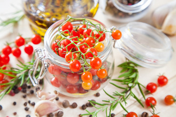 tomatoes in a jar, rosemary and garlic on a wooden background, selective focus