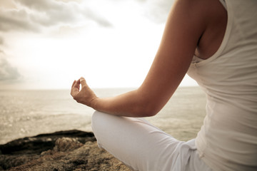 Fototapeta na wymiar Woman meditating in a yoga pose on the beach