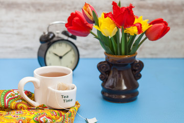 tea, tulips and alarm clock on a table, selective focus