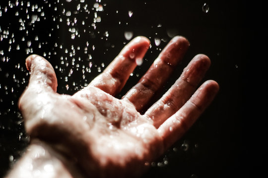Open human hand under water drops