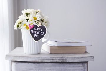 Fresh daisy flowers in white cup with happy mothers day letter