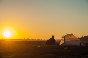 man sit front of camping tent glow up with sunrise in morning